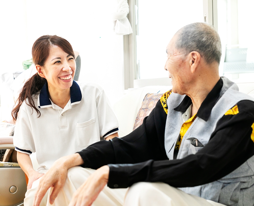 笑顔でお話しするイズミの介護施設ご利用者さまと働くスタッフ